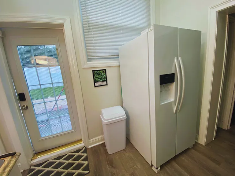 Property includes a refrigerator, trash bin, and a decorative rug.