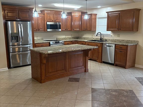 Renovated kitchen with granite countertops, wood cabinetry, center island, and tile flooring. Updated 5 years ago with stainless steel appliances, modern lighting, and plenty of storage space.