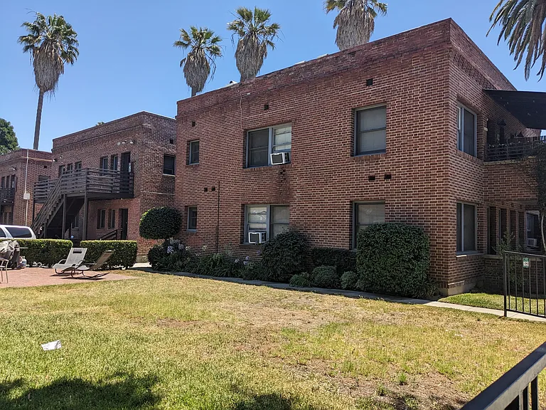 Sundeck with barbeque and grassy yard at The Villas Apartments in Pasadena, California.