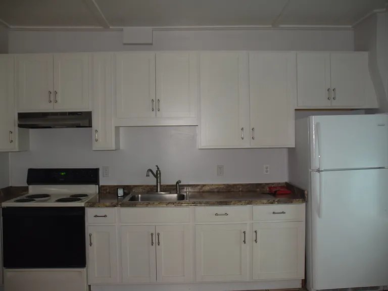 Large eat-in kitchen with new fridge, tile floor, electric range, newer cabinets, back door to back porch w/ stairs to ground level.
