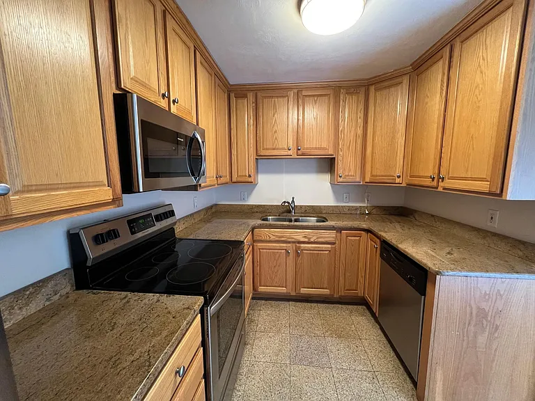Kitchen with stainless appliances including stove, microwave, refrigerator, garbage disposal, and dishwasher. Granite countertops and tile flooring.