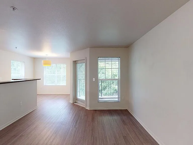 Apartment living room with wood-style flooring and patio or balcony in select homes.