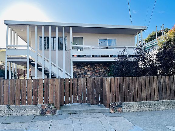 3138 California seen from the street. There is a fenced patio area. The larghe balcony for Apt 4 is shown.