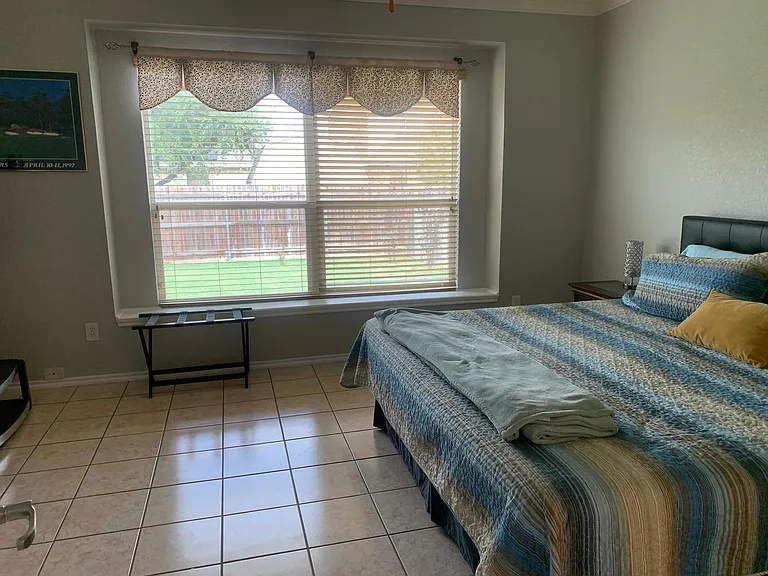 Master bedroom has a window seat with views of the backyard. Wood blinds can be adjusted for more light or privacy.