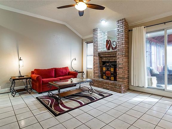 Another view of the family room, ceramic tile floor, remote controlled ceiling fan, brick, wood burning fireplace.  The sliding glass door opens to a sunroom.