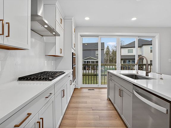 A modern, well-equipped kitchen with white cabinets, stainless steel appliances, and a view of a res