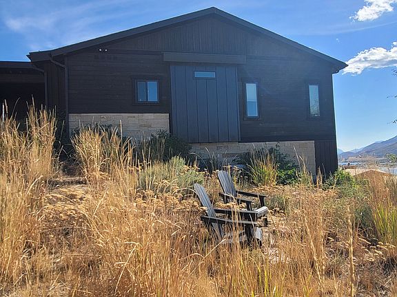 Private end unit, no adjacent structure. Sitting area with 2 Adirondack chairs.