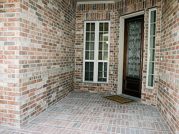The front porch features a a leaded glass door and brick flooring.