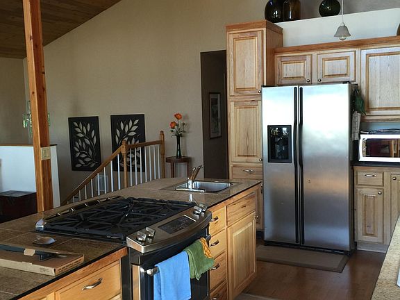 ABOUT 2/3 OF KITCHEN, NOTE THE OFF-SET VAULTED CEILING WITH HORIZONTAL WINDOWS, DIFFERENT ANGLES ON THE ROOF. KITCHEN IS ON SOUTH SIDE OF THE HOME. DISTANT STEP RAILING IS FROM THE MID-ENTRY FRONT DOOR