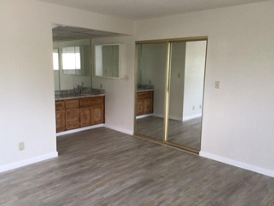 Living space with vanity in view. Behind mirrored doors is shower/toilet on 1 side and walk in closet on other side.