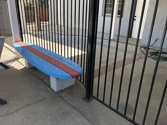 Surfboard seat by pool under patio cover