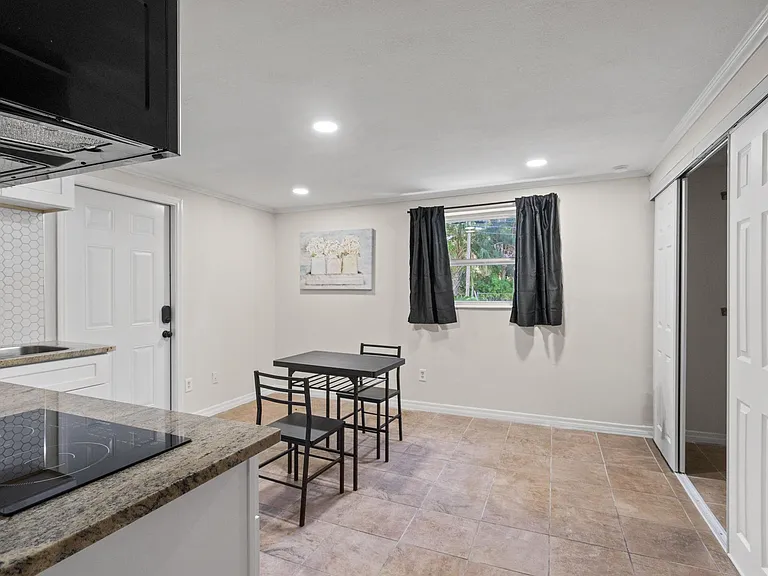 Dedicated dining nook beside the kitchen, with tile flooring, recessed lighting, and a window with curtain panels.