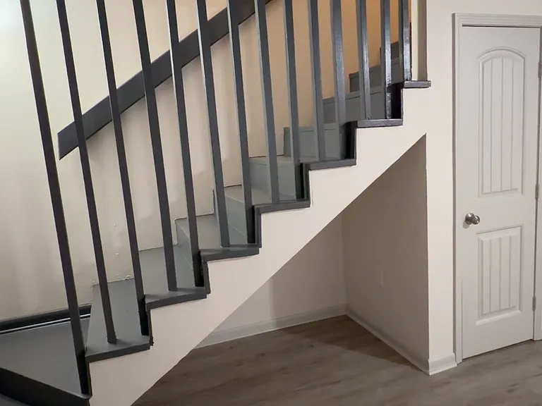 Stylish staircase with modern railing and a convenient under-stair area - perfect for extra storage or a small setup space.