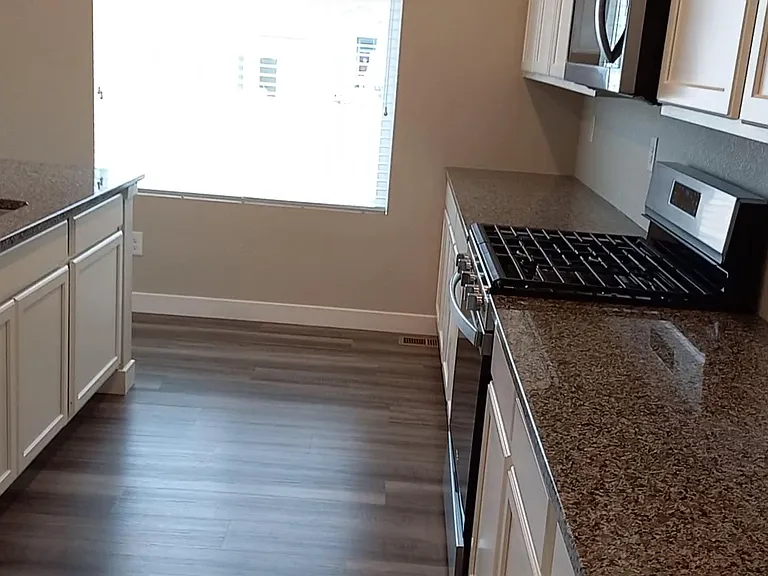 Island on the left. To the right, Granite back-counter with gas cook surface and electric oven, looking northeast, window to back yard.