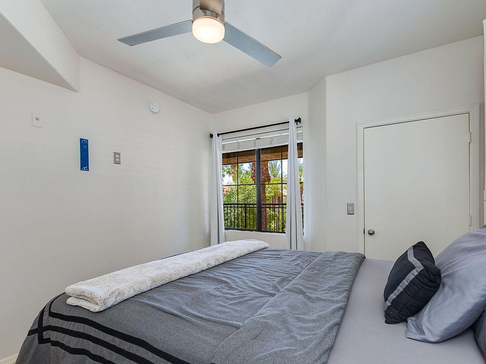 Well-sized bedroom with a ceiling fan, comfortable bed space, and a large window with curtains and pleasant outdoor views.