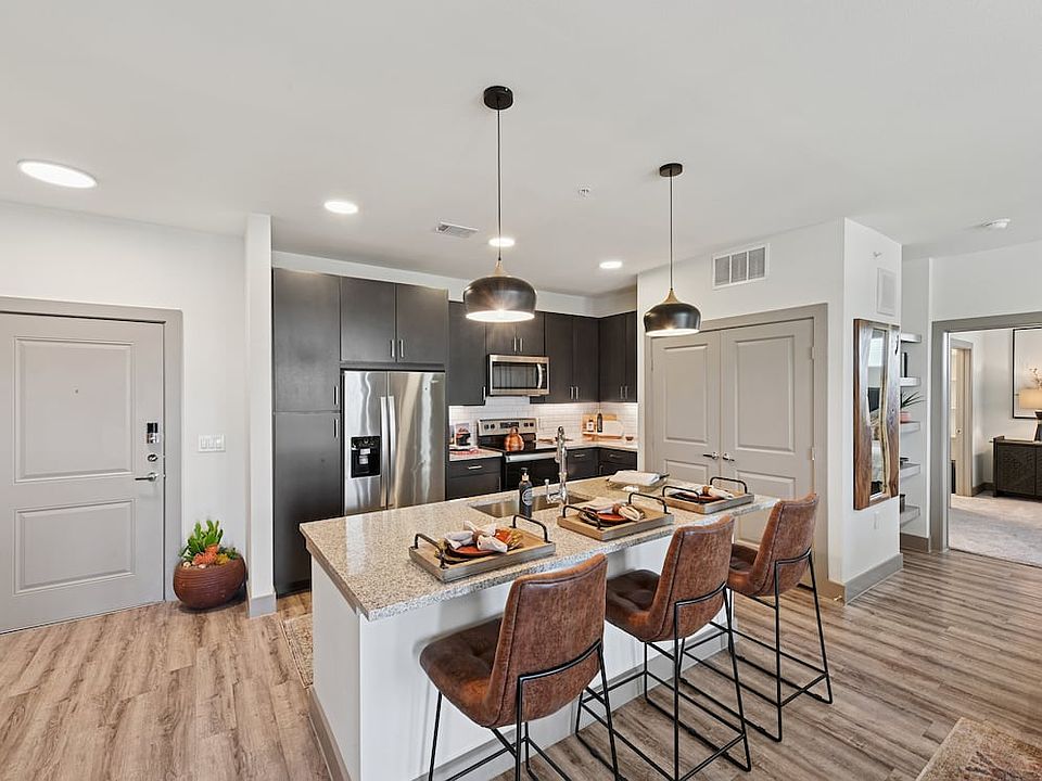 Kitchen with espresso cabinetry, speckled granite countertops, white subway tile backsplash, stainless steel appliances, and hard surface flooring