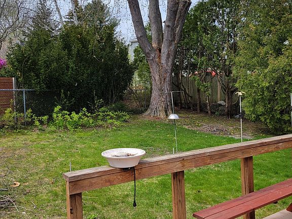 Deck off mudroom and private backyard with raspberries and rhubarb