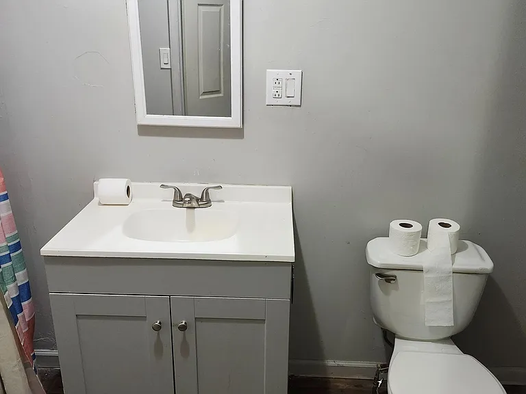 Functional bathroom featuring a single-sink vanity with storage, framed mirror, and durable flooring for easy upkeep.