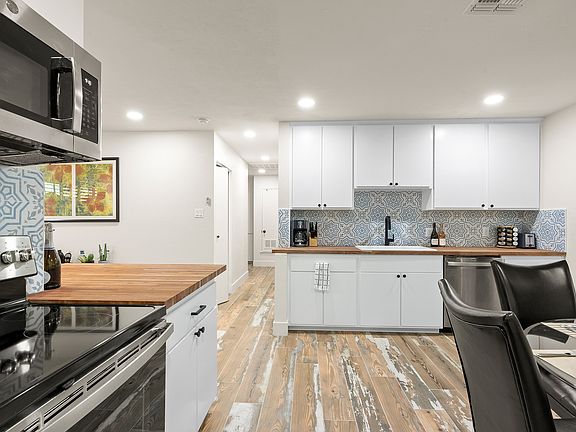 Kitchen with butcher block counter tops, ample cabinets & cute backsplash