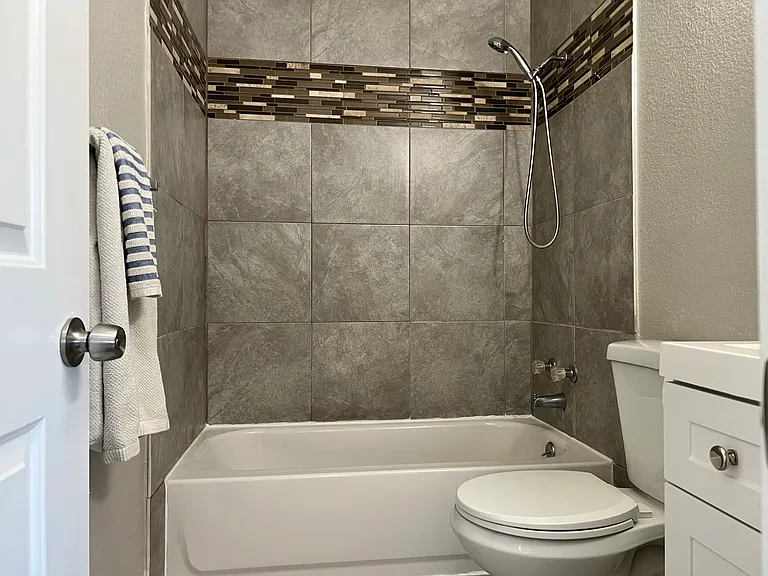 Beautifully detailed bathroom featuring clean gray tile work accented by a modern brown glass tile strip.
