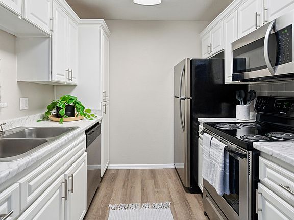Enjoy a stylish kitchen featuring white cabinetry, stainless steel appliances, and marble-style countertops.