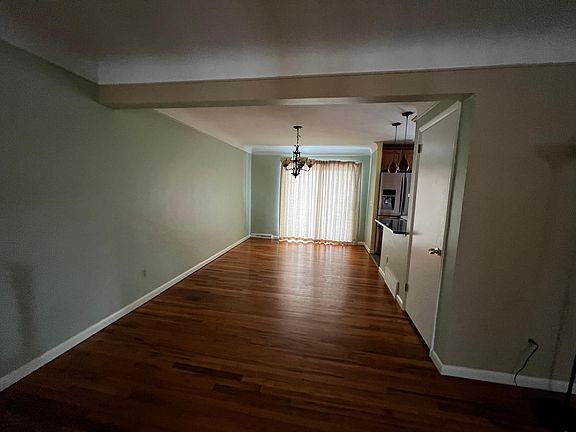 Standing in living room, facing dining room (kitchen to its right) and looking at patio door that leads out to the backyard.
