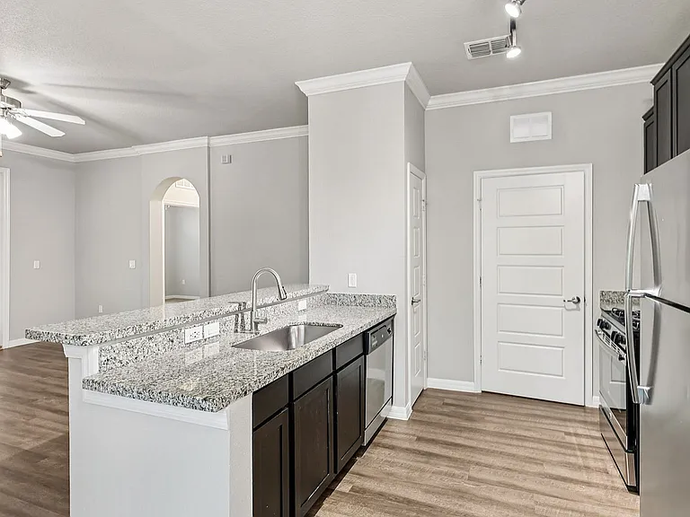 Sleek modern kitchen with granite countertops, stainless steel appliances, and elegant wood flooring in a bright, open-concept space.