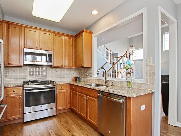 ALL STAINLESS KITCHEN WITH TILED BACK SPLASH AND OPENS TO LIVING AREA AND DINING