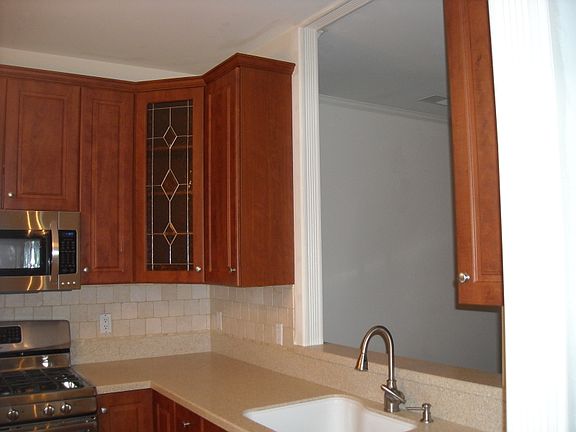 42" Cherry cabinetry with corner cabinet glass inlay and bottom lazy suzie. Corian counter tops and tiled backsplash.