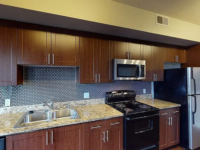 Apartment kitchen with granite countertops and wood-style flooring.
