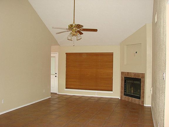 Another view of the family room with high ceilings and wood blinds. Tile fireplace as well.