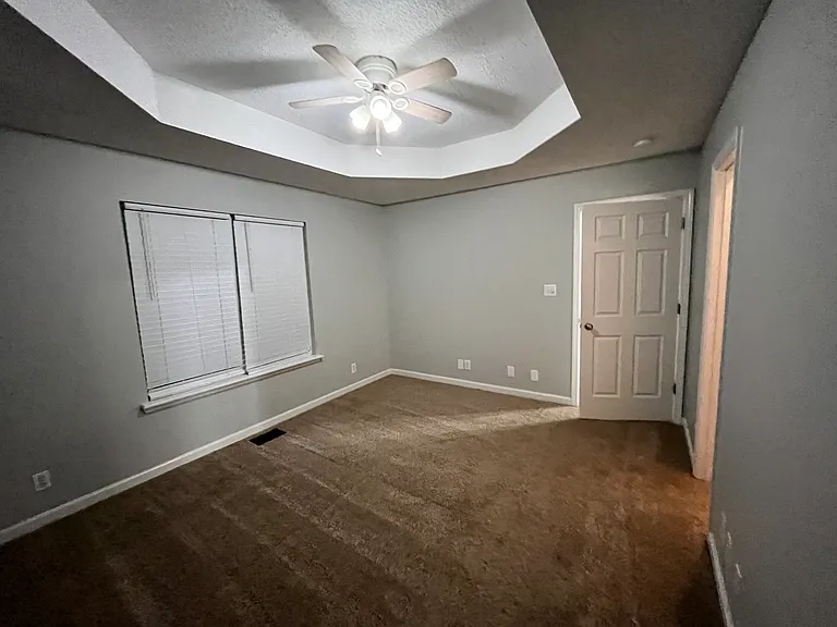Primary bedroom with vaulted ceiling and fan.