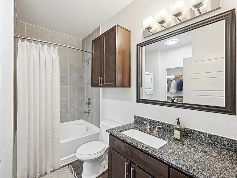Refreshed Finishes bath with espresso cabinetry, speckled granite countertops, and hard surface flooring