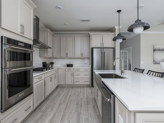 Large Kitchen with modern pendant lighting and kitchen island. Model Home Representation.