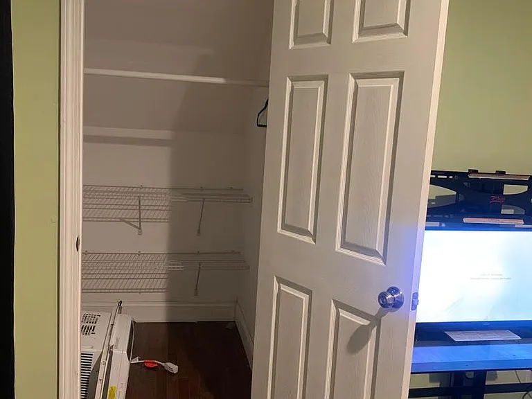 Bedroom closet with built-in shelving for organized clothing, linens, and personal storage off the sleeping area.