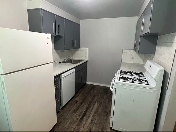 Galley style kitchen with gas cooking range, dishwasher, & fridge.