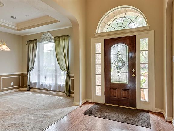 Foyer with wood floors and art niche. Archway is the entrance to formal dining room. Dining room with trayed ceiling, crown mold