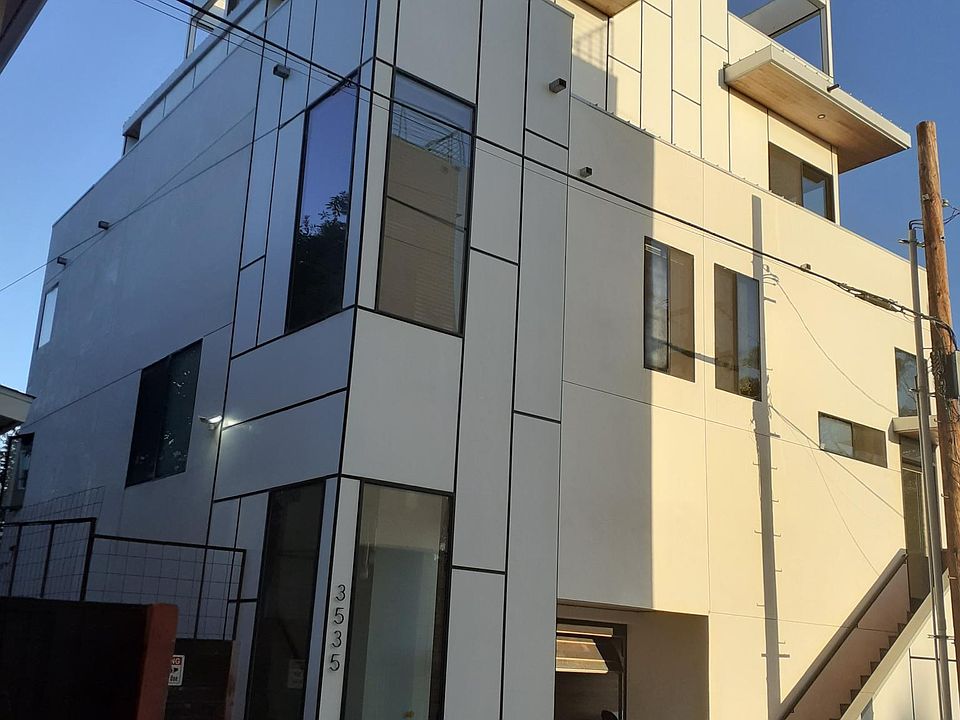Building exterior showing four floors, mezzanine balcony and top floor balcony. Townhouse occupies half of building.