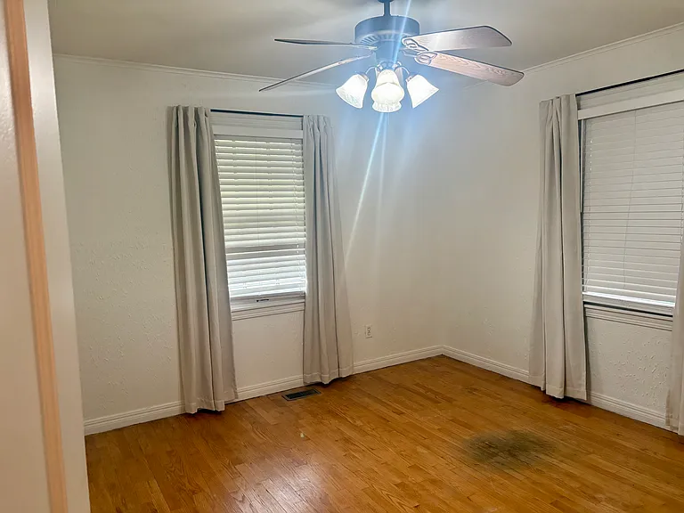 Primary bedroom with window facing front yard and new ceiling fan.