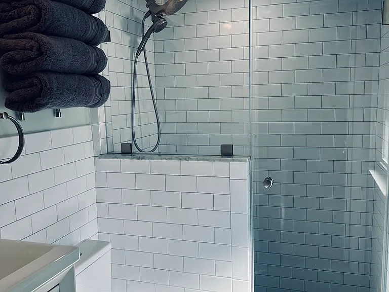 Private bath with floating sink, storage and shower.