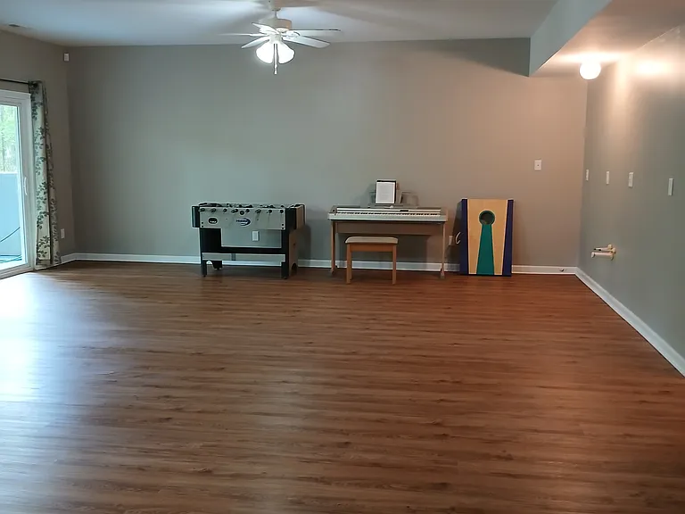 Rec room has foos ball table, keyboard, corn hole game