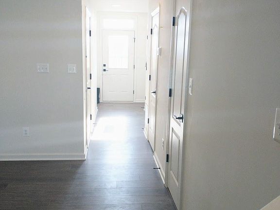 Entry hallway, with garage entry into house. In this hallway, find the coat closet, utilities closet, 1/2 bathroom, and under-staircase storage