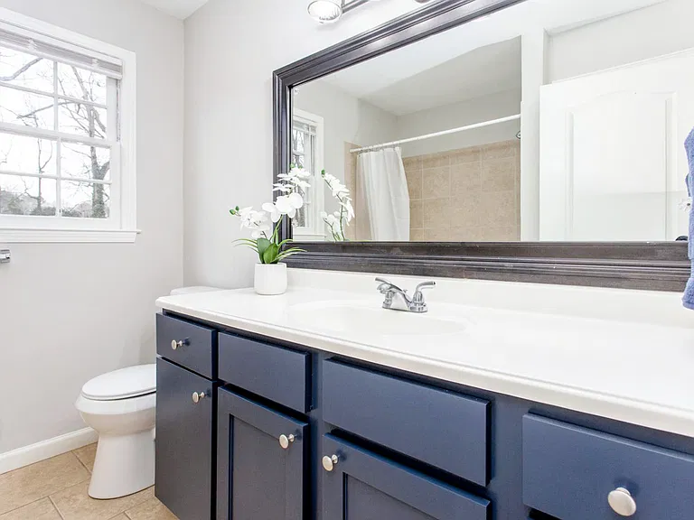 Shared upstairs bath with large vanity and closet for storage.