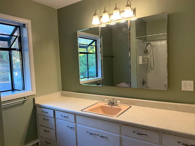 bathroom with 3 mirrors, 2 cabinets inside, wide countertop space, tub and shower combo