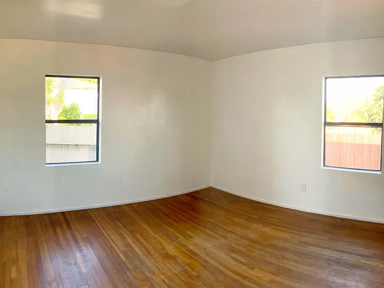 Bedroom at east corner of house, window on the left faces alley, window on the right faces backyard