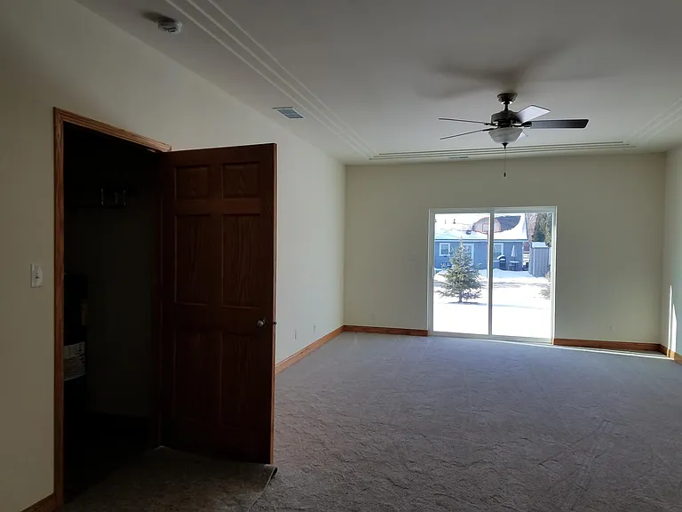 Tray Ceiling In Living Room With Ceiling Fan & Sliding Glass Door To Poured Patio.