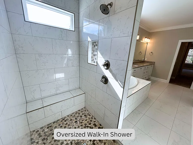 Oversized walk-in tile shower with two shower heads and seating bench