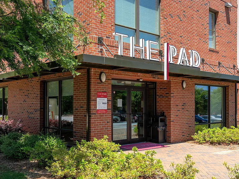 Main entrance to The Pad apartment community with red brick exterior and modern signage.