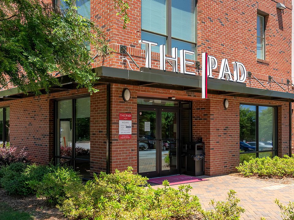 Main entrance to The Pad apartment community with red brick exterior and modern signage.
