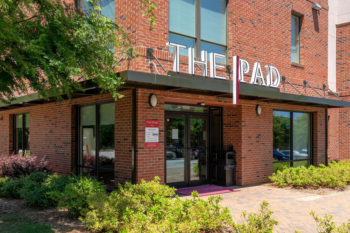 Main entrance to The Pad apartment community with red brick exterior and modern signage.